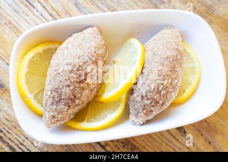 Kufta oder gehackte putenschnitzel mit Zitrone auf einem Teller ist ein traditionelles Gericht in den türkischen und kaukasischen Völkern Stockfoto