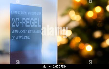 Dresden, Deutschland. 22nd. November 2021. Ein Schild an der Tür vor einem Schuhgeschäft weist auf die Regel von 2G hin. Angesichts der rasant steigenden Corona-Zahlen werden ab diesem Montag in Sachsen strengere Regeln zur Bekämpfung der Pandemie gelten. Quelle: Robert Michael/dpa-Zentralbild/dpa/Alamy Live News Stockfoto