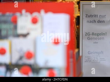 Dresden, Deutschland. 22nd. November 2021. Ein Schild in einer Buchhandlung weist auf die Regel von 2G hin. Angesichts der rasant steigenden Corona-Zahlen werden ab diesem Montag in Sachsen strengere Regeln zur Bekämpfung der Pandemie gelten. Quelle: Robert Michael/dpa-Zentralbild/dpa/Alamy Live News Stockfoto