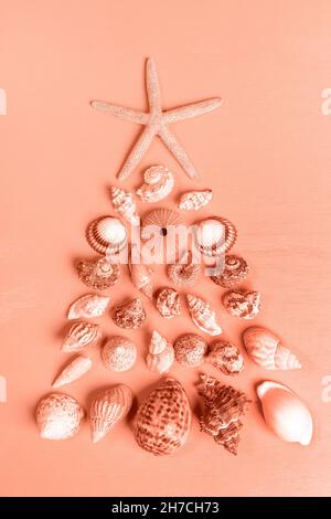 Viele verschiedene Muscheln und ein Seesterne sind in Form eines Weihnachtsbaums angelegt. Alternativer Weihnachtsbaum. Kreativer Hintergrund für den Urlaub. Vertikale Ausrichtung Stockfoto