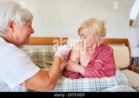 Krankenschwester oder Arzt, der einen älteren Bürger zum Schutz vor Infektionskrankheiten impft Stockfoto