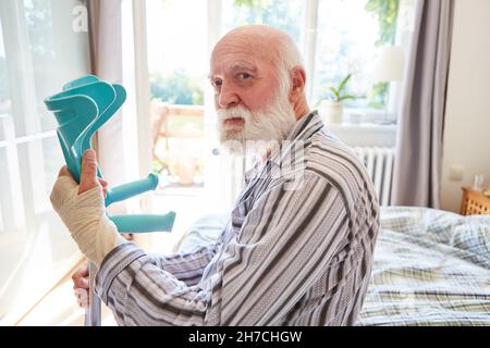 Alter Senior mit gebrochenem Handgelenk und Gehhilfe in der Klinik für Reha Stockfoto