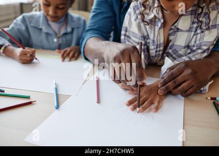 Nahaufnahme eines afroamerikanischen Vaters mit zwei Mädchen, die zu Hause zeichnen und die Hände verfolgen, Platz kopieren Stockfoto