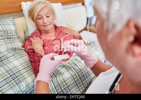 Krankenschwester oder Arzt, die zu Hause einen CRP-Test an einer kranken älteren Frau im Bett macht Stockfoto
