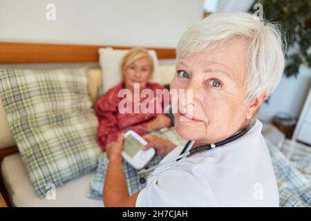 Krankenschwester mit Blutdruckmessgerät zur Messung des Blutdrucks älterer Frauen zu Hause Stockfoto