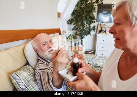 Krankenschwester verteilt Medikamente an kranke alte Mann im Bett im Pflegeheim Stockfoto