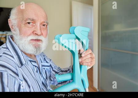 Alter Mann als Patient mit Krücken nach einem Schlaganfall in einer Reha-Klinik oder in einem Pflegeheim Stockfoto