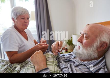 Senior als Patient mit Asthma erhält Cortison-Spray von der geriatrischen Krankenschwester im Pflegeheim Stockfoto