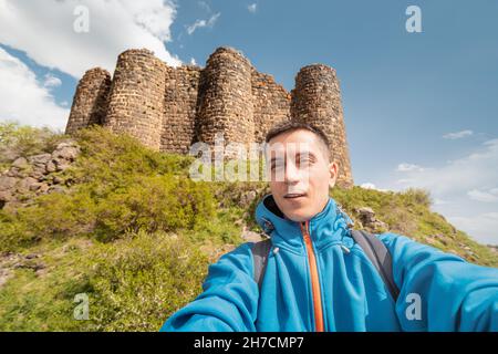 Männlicher Reisender macht ein Selfie-Foto vor dem Hintergrund der Ruinen der alten Festung Amberd in Armenien. Stockfoto