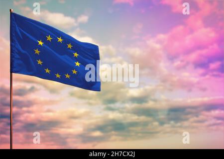 Flatterndes Modell der EU-Flagge mit dem Platz für Ihren Text auf einem farbenprächtigen, wolkigen Hintergrund. Stockfoto