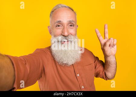 Foto von fröhlichen reifen Mann nehmen Selfie zeigen Finger Frieden V-Symbol isoliert über gelben Hintergrund Stockfoto