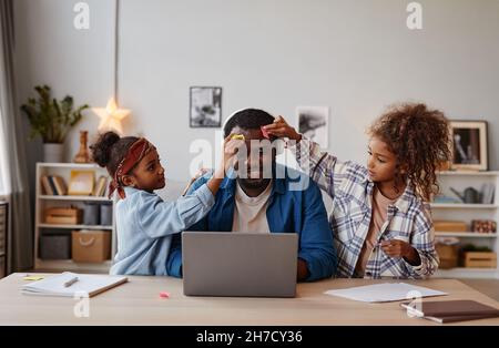 Portrait von zwei Kindern, die mit einem glücklichen Vater spielen, der von zu Hause aus arbeitet, Platz kopieren Stockfoto