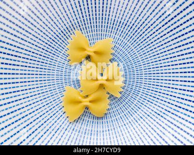 Hellgelbe Pasta in Form eines Schmetterlings auf einer Keramikplatte, Nahaufnahme, Draufsicht. Stockfoto