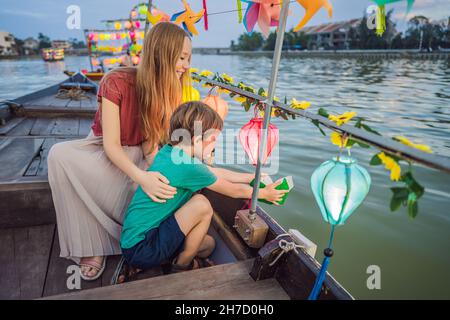 Glückliche Familie Mutter und Sohn von Reisenden reiten auf einem Nationalboot auf dem Hintergrund der alten Stadt Hoi, Vietnam. Vietnam öffnet sich danach wieder für Touristen Stockfoto