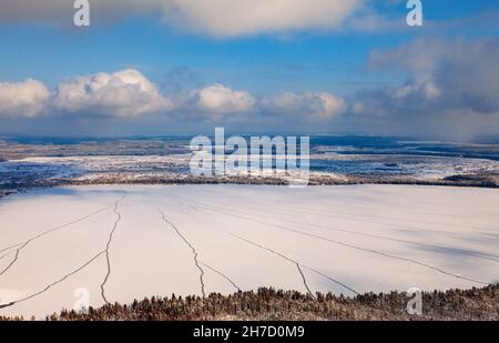 Luftfoto des Winterwaldsees während eines sonnigen Tages in Westsibirien. Schneit von weißen Wolken mit niedrigem Kumulus. Stockfoto