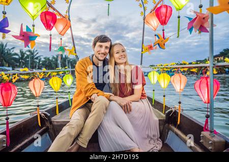Ein glückliches Paar von Reisenden fährt auf einem Nationalboot auf dem Hintergrund der alten Stadt Hoi in Vietnam. Vietnam öffnet sich nach der Quarantäne wieder für Touristen Stockfoto