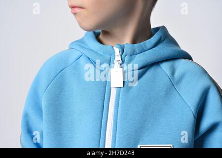 Nahaufnahme von Kid Boy in blauem Jumpsuit oder Hoodie mit Reißverschluss stehend mit gedrehtem Kopf und Blick zur Seite Stockfoto