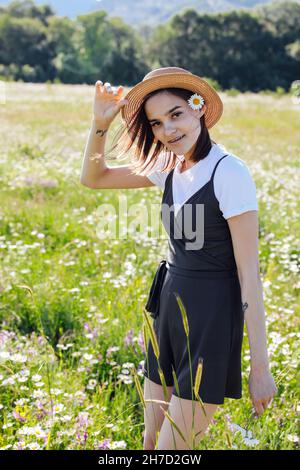 Frau in einem Kleid, die mit Gänseblümchen durch das Feld läuft Stockfoto