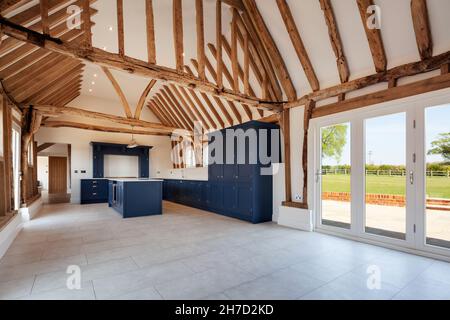 Great Sampford, Essex - April 16 2020: Luxuriöse Küche in großer renovierter britischer Scheune, dominiert von gewölbter Decke mit zahlreichen freiliegenden Holzbalken Stockfoto