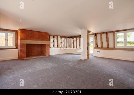 Great Sampford, Essex - April 16 2020: Leeres Wohnzimmer in einer großen, kürzlich umgebauten Scheune mit freiliegenden Hölzern und einem offenen Kamin. Stockfoto