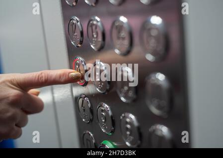 Frau drückt den Knopf mit ihrem Zeigefinger auf die 8th. Etage des Aufzugs Stockfoto