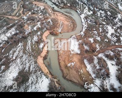 Im Winter paddelt der Mensch auf einem orangefarbenen Floßboot im Fluss. Luftdrohnenaufnahme. Stockfoto