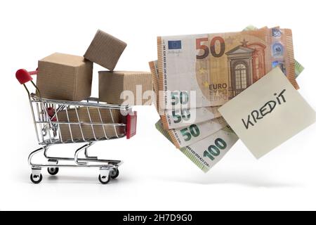 Pakete in einem kleinen Einkaufswagen und Bargeld sowie Notiz mit Aufschrift Kredit als ein Konzept von Schulden und Verschuldung isoliert auf weißem Hintergrund Stockfoto