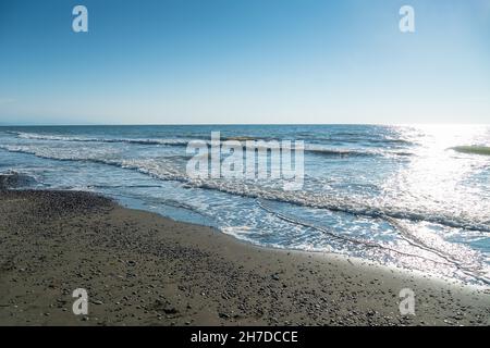 Sandstrand mit Kieselsteinen, Meereswellen Rollen an einem sonnigen Tag auf den Strand Stockfoto