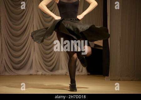 Das Mädchen tanzt in einem schwarzen Kleid. Eine Frau zeigt eine Tanzbewegung. Der Student tritt mit einem Tanz auf der Bühne auf. Stockfoto