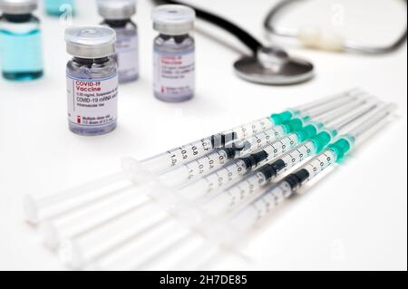 Coronavirus-Impfung gegen SARS-CoV-2, medizinische Spritzen, jeweils mit einer Dosis COVID-19-Impfstoff; mit mehreren Glasfläschchen und einem medizinischen Stethoskop Stockfoto