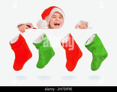 Ein Kind in einem Weihnachtsmannkostüm guckst raus und lacht über die Socken, die an den Weihnachtsstiefeln hängen. Stockfoto