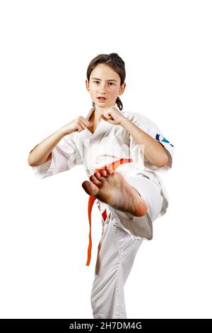 Karate Mädchen auf einem weißen Hintergrund. Eine athletische kaukasische Brünette in einem weißen Kimono beschäftigt sich mit Kampfkünsten und übt Tritte. Kontaktieren Sie den Sport. H Stockfoto