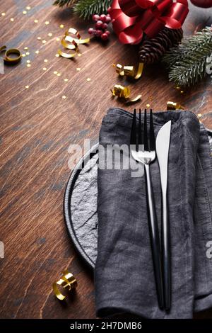 Weihnachtstisch mit schwarzer Farbe mit Tannenzweigen, Weihnachtskugeln und Lebkuchen auf altem Holzhintergrund für Weihnachtsgrüße. Mer Stockfoto