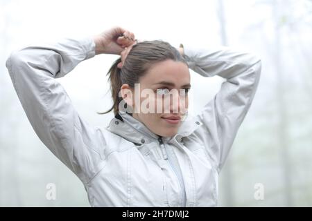 Glücklicher Wanderer, der Pferdeschwanz in einem nebligen Wald macht Stockfoto