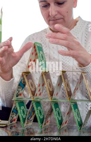 Hände einer Frau, die einen Turm aus Spielkarten stapelt. Nahaufnahme. Selektiver Fokus. Bewegungsunschärfe. Stockfoto
