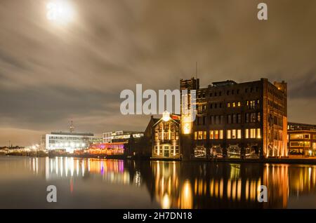 Haarlem, Niederlande, 19. November 2021: Nachtansicht mit Licht des Mondes des Spaarne-Flusses mit der alten Droste-Fabrik und anderen industriellen h Stockfoto