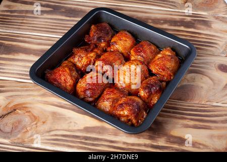 Gebratene Hähnchenschenkel auf Backblech. Gekochte gebackene Hühnerteile liegen auf einem Holztisch. Nahaufnahme, Draufsicht Stockfoto