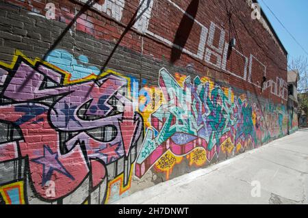 Abstraktes buntes Fragment von Graffiti-Gemälden auf alten Ziegelwänden. Street Art Komposition mit Teilen von Unwri Stockfoto