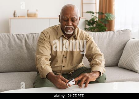 Ältere Afrikanische Männliche Mit Pulsoximeter Messung Sättigungsniveau In Innenräumen Stockfoto