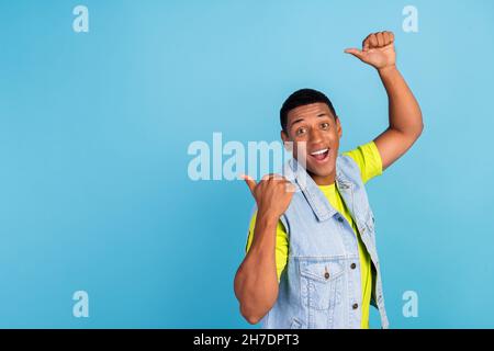 Profil Seite Foto von jungen afro Mann zeigen Daumen leeren Raum werben empfehlen isoliert über blauen Hintergrund Stockfoto