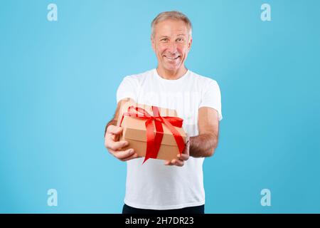 Reifer Mann Hält Und Schenkt Weihnachtsgeschenk Im Studio Stockfoto