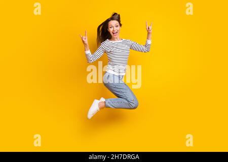 Foto in voller Größe von sorglosen Brünette Millennial Dame springen zeigen Rock tragen Pullover Jeans Schuhe isoliert auf gelbem Hintergrund Stockfoto