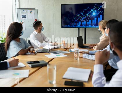 Eine Gruppe Multikultureller Kollegen, Die Medizinische Masken Tragen, Hat Ein Geschäftstreffen Im Büro Stockfoto