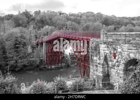 Blick auf die historische Eisenbrücke bei Ironbridge, Shropshire, England, Großbritannien, über den Fluss Severn - monochromes Bild mit roter Brücke, Farbspritzer Stockfoto