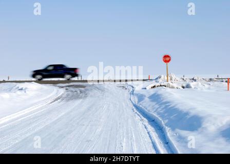 Stop-Schild an der Kreuzung im Winter auf einer verschneiten Straße mit LKW oder Auto fahren durch verschwommene verschwommen verschwommen Stockfoto