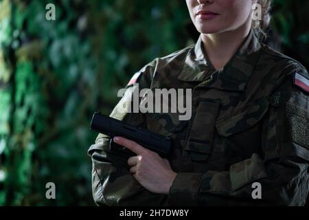 Vor ihr steht eine Soldatin mit gefalteten Armen und einem Gewehr in der Hand. Stockfoto