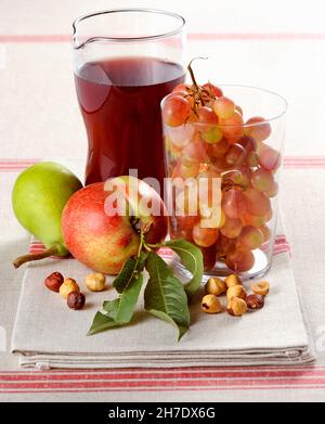 Ein Arrangement aus frischem Obst, Haselnüssen und Rotwein Stockfoto