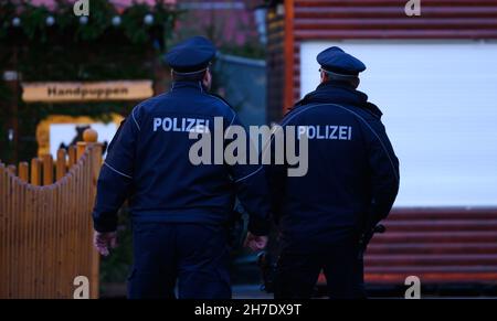 Dresden, Deutschland. 22nd. November 2021. Während des Rückbaus des Dresdner Striezelmarktes laufen Polizeibeamte über den Altmarkt. Angesichts der rasant steigenden Corona-Zahlen gelten ab diesem Montag unter anderem in Sachsen und Schleswig-Holstein strengere Regeln zur Bekämpfung der Pandemie. Sachsen, das besonders betroffen ist, schränkt große Teile des öffentlichen Lebens ein. Quelle: Robert Michael/dpa-Zentralbild/dpa/Alamy Live News Stockfoto