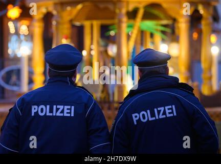 Dresden, Deutschland. 22nd. November 2021. Während des Rückbaus des Dresdner Striezelmarktes laufen Polizeibeamte über den Altmarkt. Angesichts der rasant steigenden Corona-Zahlen gelten ab diesem Montag unter anderem in Sachsen und Schleswig-Holstein strengere Regeln zur Bekämpfung der Pandemie. Sachsen, das besonders betroffen ist, schränkt große Teile des öffentlichen Lebens ein. Quelle: Robert Michael/dpa-Zentralbild/dpa/Alamy Live News Stockfoto