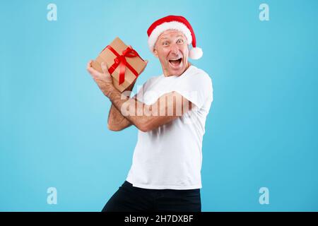 Reifer Mann Hält Und Zeigt Weihnachtsgeschenk Im Studio Stockfoto
